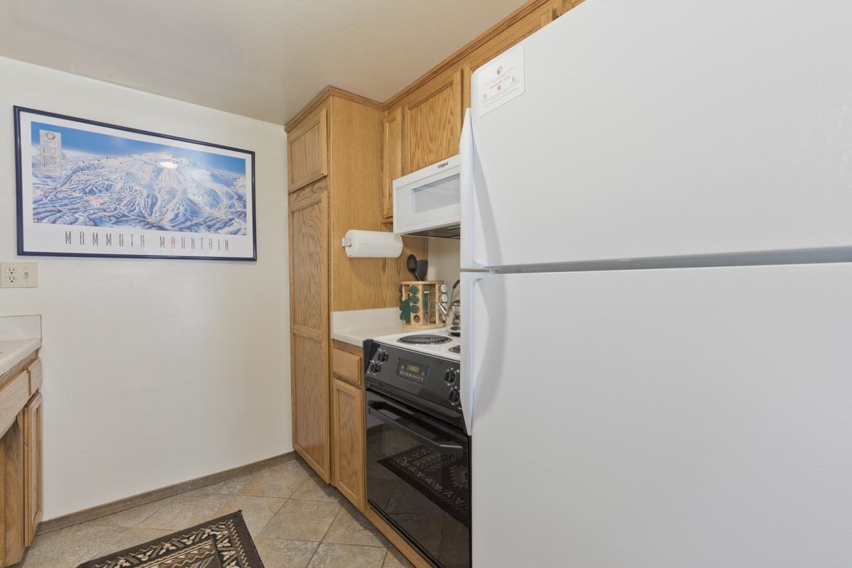 244 Lakeview Boulevard, Unit 149 Mammoth Lakes, CA 93546 - Photo 19 of 29 Kitchen with white appliances, brown cabinetry, and light countertops