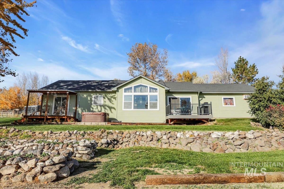 View of front facade with a hot tub, a front yard, and a deck