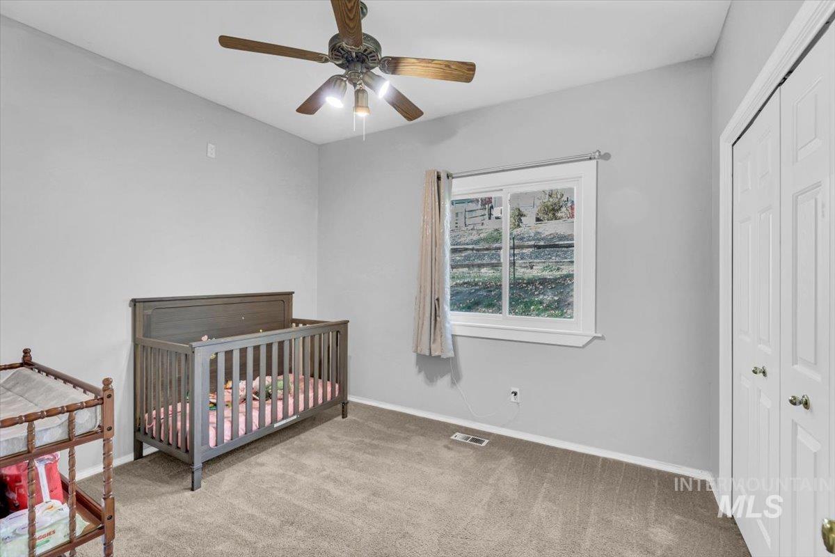 23919 Tyler Lane Middleton, ID 83644 - Photo 17 of 48 Bedroom featuring light carpet, a crib, ceiling fan, and a closet