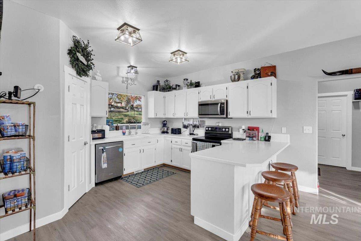 23919 Tyler Lane Middleton, ID 83644 - Photo 20 of 48 Kitchen with white cabinetry, light countertops, light wood-style floors, a kitchen breakfast bar, and appliances with stainless steel finishes