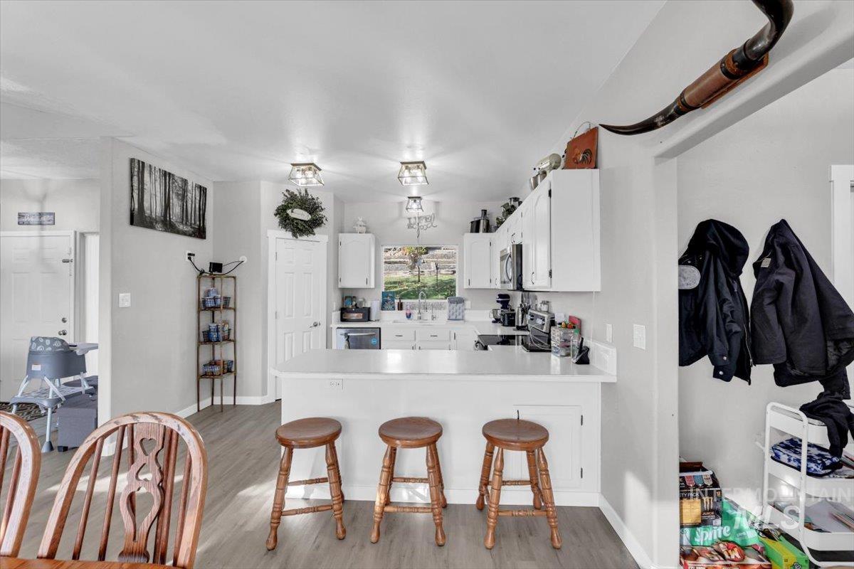 23919 Tyler Lane Middleton, ID 83644 - Photo 22 of 48 Kitchen with light countertops, a breakfast bar, white cabinetry, a peninsula, and light wood-style floors