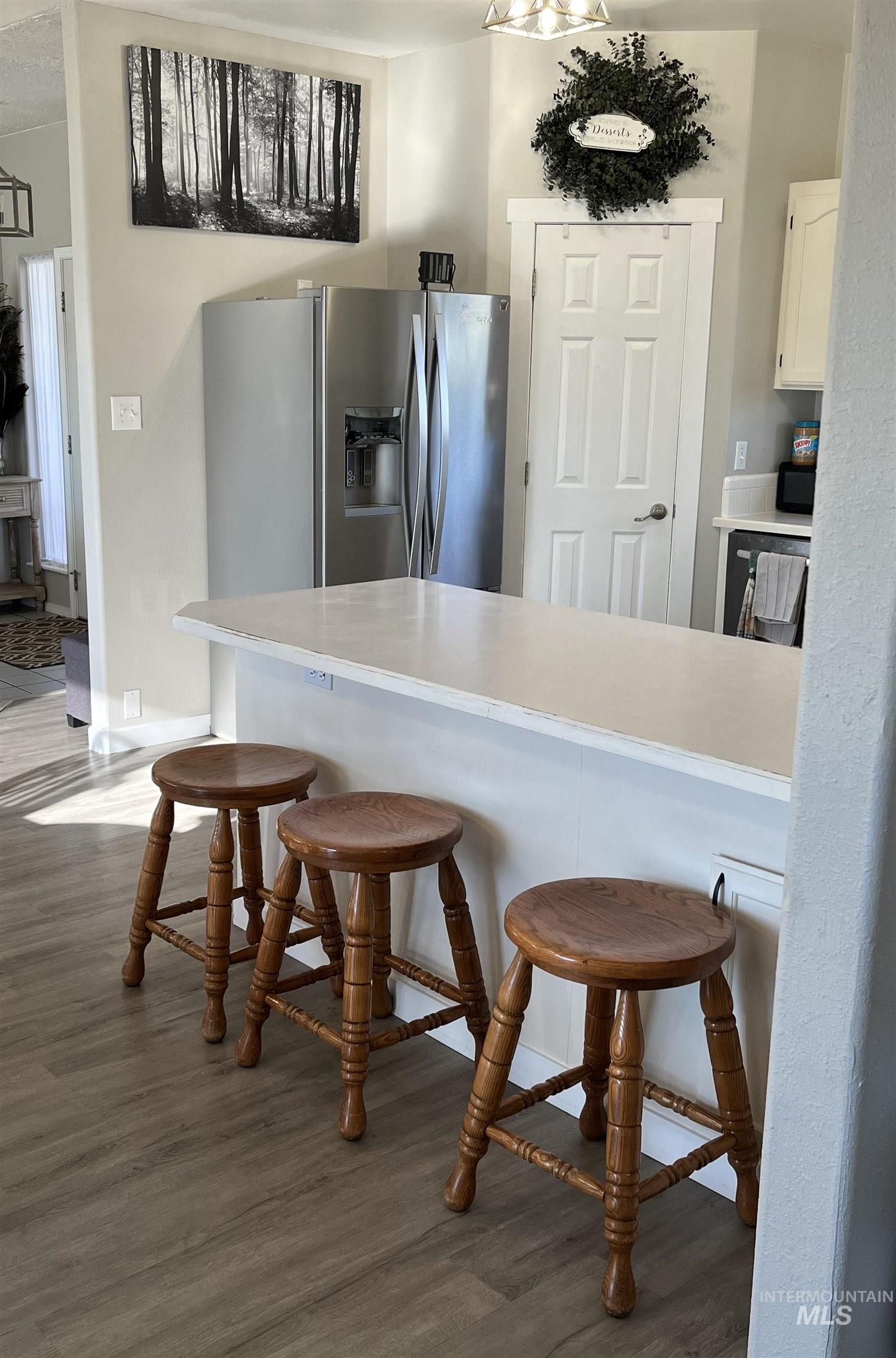 23919 Tyler Lane Middleton, ID 83644 - Photo 23 of 48 Kitchen featuring a breakfast bar, light countertops, white cabinets, stainless steel fridge, and dark wood-style flooring