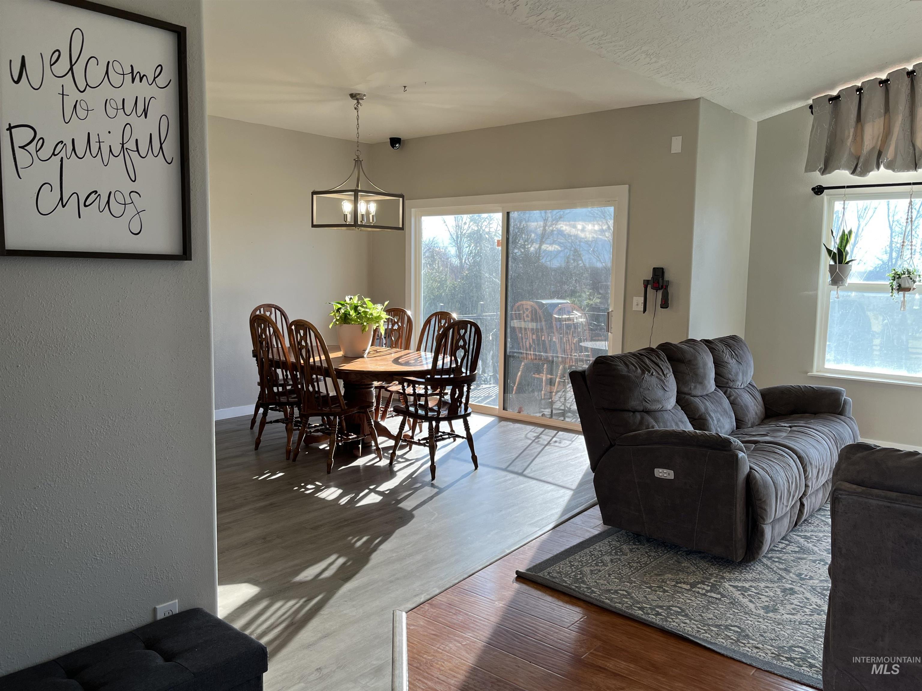 23919 Tyler Lane Middleton, ID 83644 - Photo 26 of 48 Living room with wood finished floors, a chandelier, a textured ceiling, and a textured wall