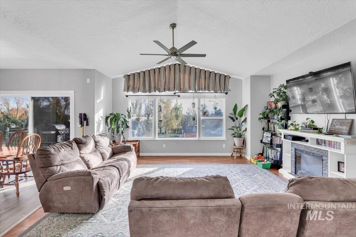23919 Tyler Lane Middleton, ID 83644 - Photo 32 of 48 Living room featuring a textured ceiling, wood finished floors, lofted ceiling, a glass covered fireplace, and ceiling fan