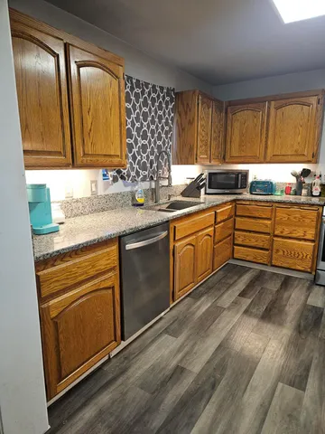 a kitchen with granite countertop stainless steel appliances sink cabinets and window