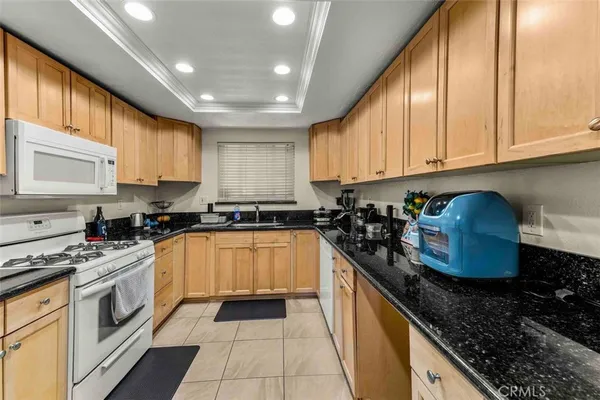 a kitchen with granite countertop a sink a stove and cabinets