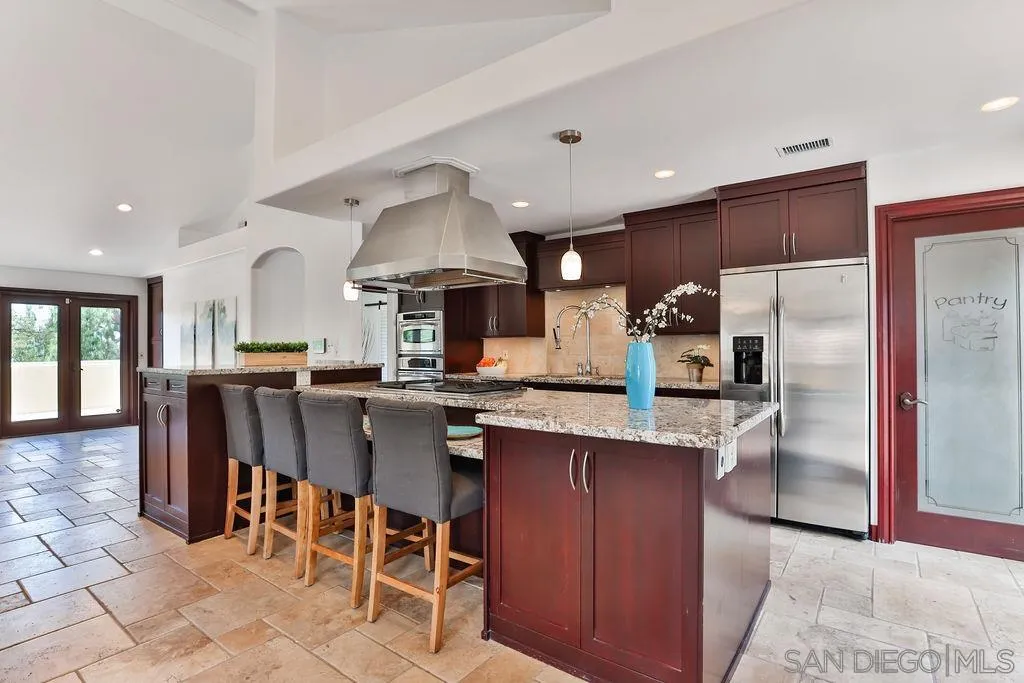 2038 Valley Rim Road El Cajon, CA 92019 - Photo 9 of 37 a kitchen with stainless steel appliances kitchen island granite countertop a table chairs sink and cabinets