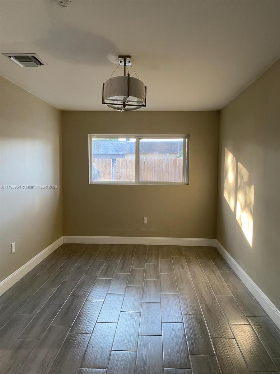 3906 Northwest 207 St Road, Unit 3906 Miami Gardens, FL 33055 - Photo 11 of 19 an empty room with wooden floor chandelier and windows