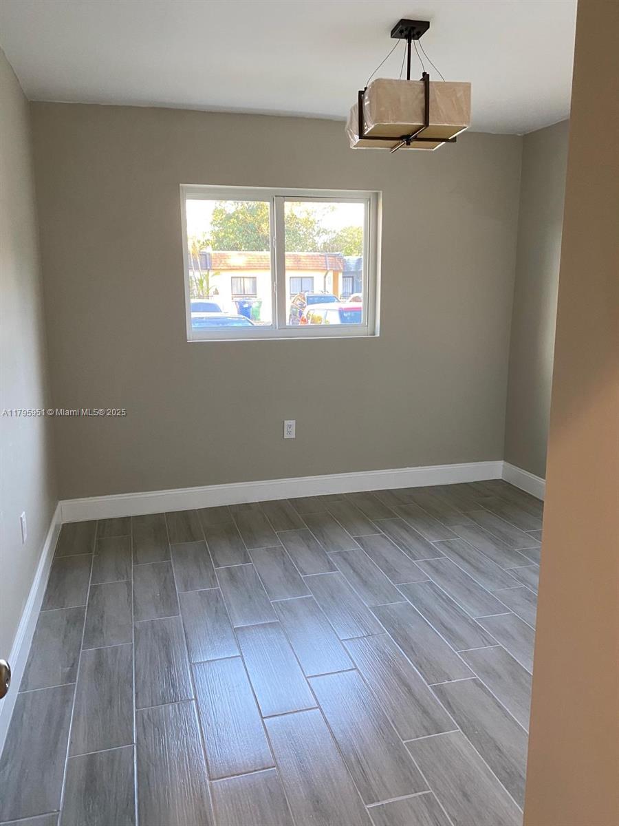 3906 Northwest 207 St Road, Unit 3906 Miami Gardens, FL 33055 - Photo 12 of 19 a view of an empty room with wooden floor and a window