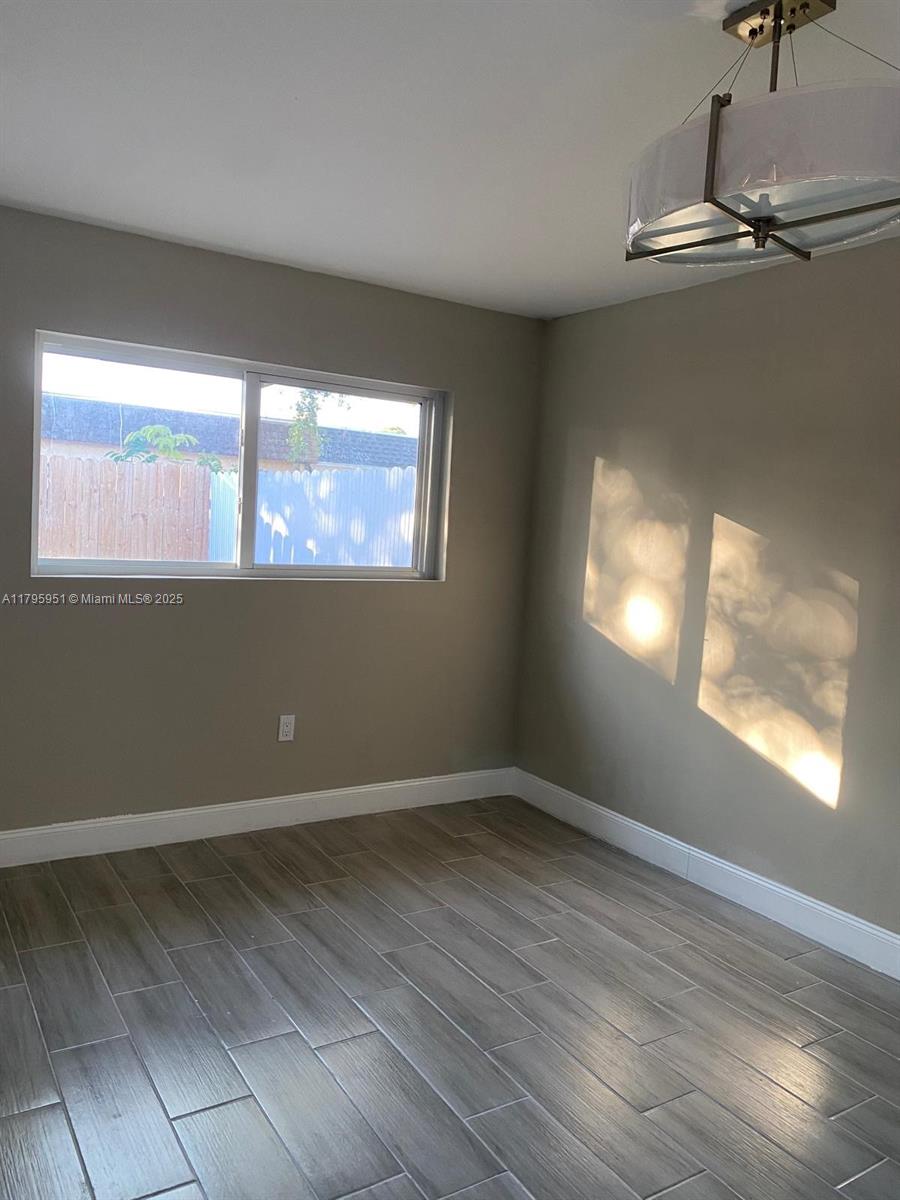 3906 Northwest 207 St Road, Unit 3906 Miami Gardens, FL 33055 - Photo 13 of 19 an empty room with wooden floor and windows