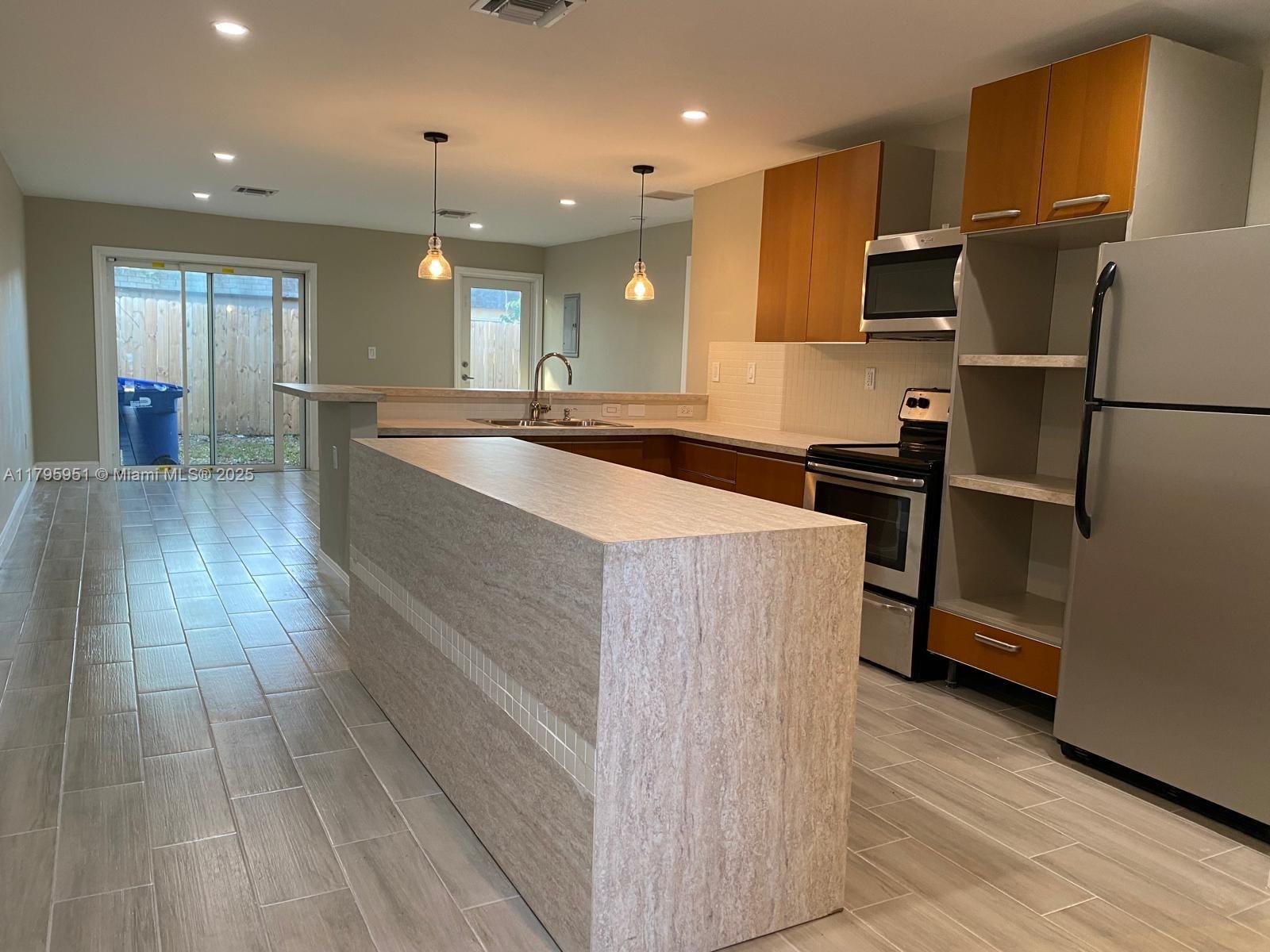 3906 Northwest 207 St Road, Unit 3906 Miami Gardens, FL 33055 - Photo 2 of 19 a large kitchen with stainless steel appliances granite countertop a refrigerator and a sink