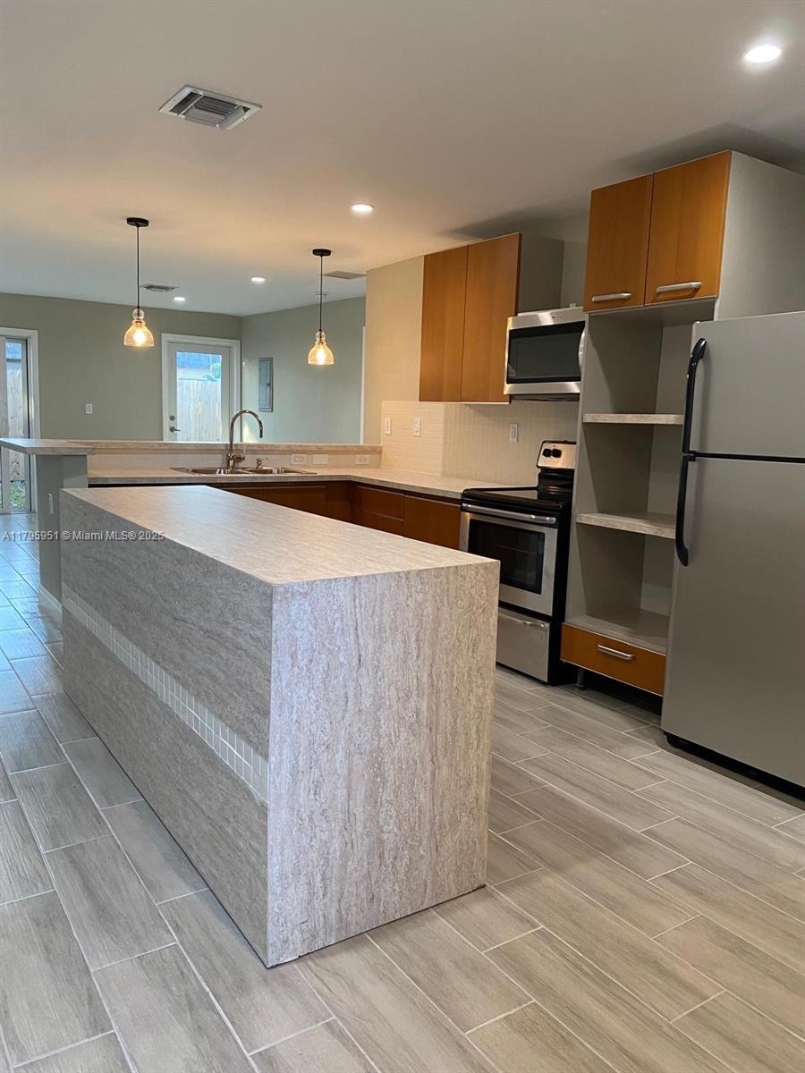 3906 Northwest 207 St Road, Unit 3906 Miami Gardens, FL 33055 - Photo 3 of 19 a kitchen with kitchen island a counter top space cabinets and stainless steel appliances