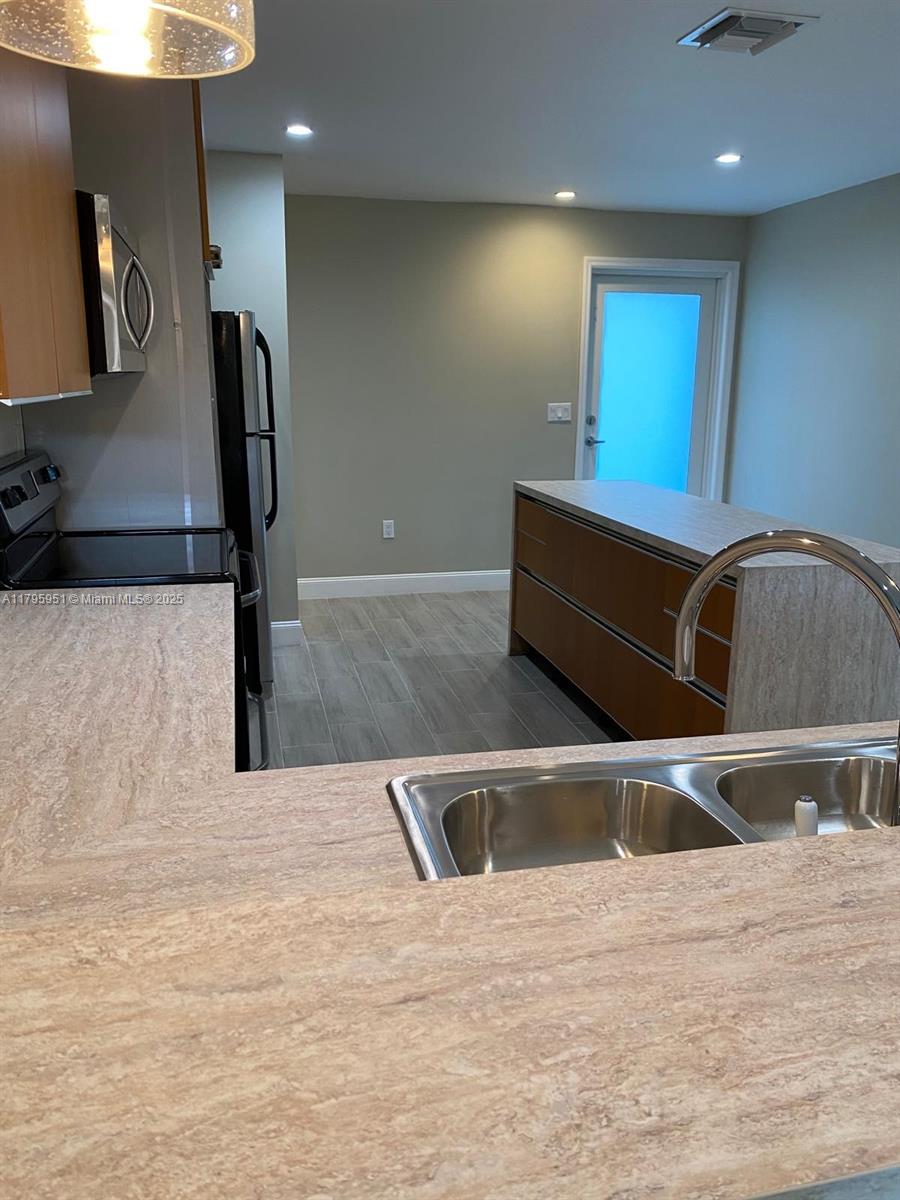 3906 Northwest 207 St Road, Unit 3906 Miami Gardens, FL 33055 - Photo 5 of 19 a kitchen with stainless steel appliances kitchen island a large counter top a stove and a sink