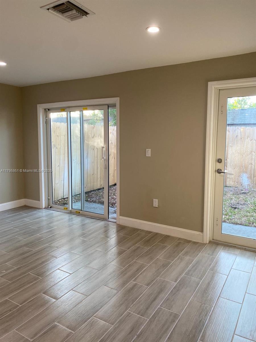 3906 Northwest 207 St Road, Unit 3906 Miami Gardens, FL 33055 - Photo 6 of 19 an empty room with wooden floor and windows