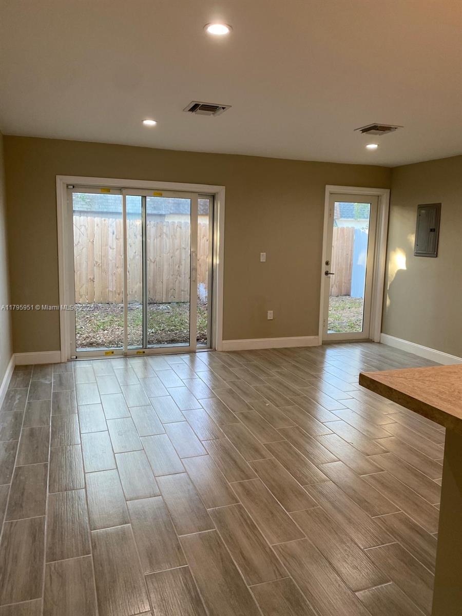 3906 Northwest 207 St Road, Unit 3906 Miami Gardens, FL 33055 - Photo 7 of 19 a view of an empty room with glass door and wooden floor