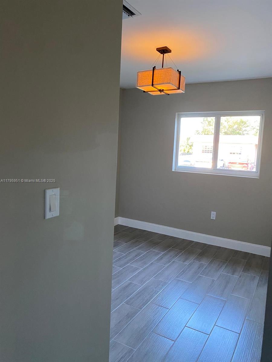 3906 Northwest 207 St Road, Unit 3906 Miami Gardens, FL 33055 - Photo 8 of 19 an empty room with wooden floor chandelier fan and windows