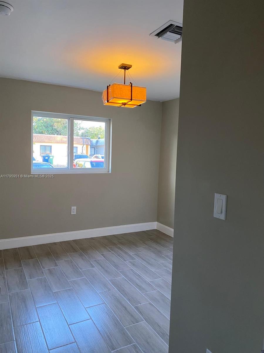 3906 Northwest 207 St Road, Unit 3906 Miami Gardens, FL 33055 - Photo 10 of 19 an empty room with wooden floor and windows