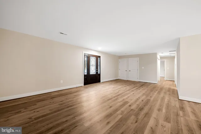 a view of an empty room with wooden floor and closet