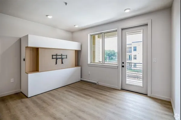 a view of an empty room with wooden floor and a window