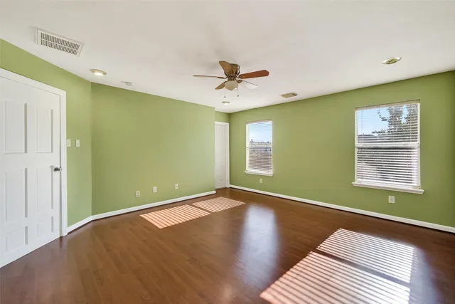 a view of a room with window a ceiling fan and wooden floor