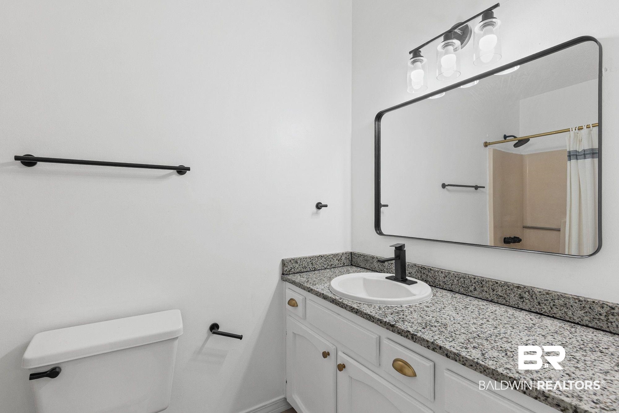 1301 Repoll Road Mobile, AL 36695 - Photo 18 of 21 Bathroom featuring a white vanity with gold-tone hardware, a speckled countertop, and an oval undermount sink with a matte black faucet