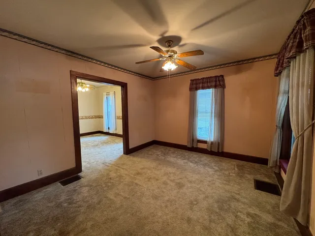 an empty room with windows and fan