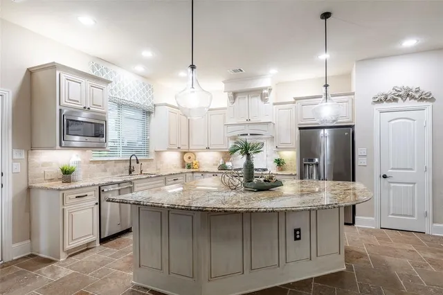a kitchen with kitchen island granite countertop stainless steel appliances a sink stove and refrigerator