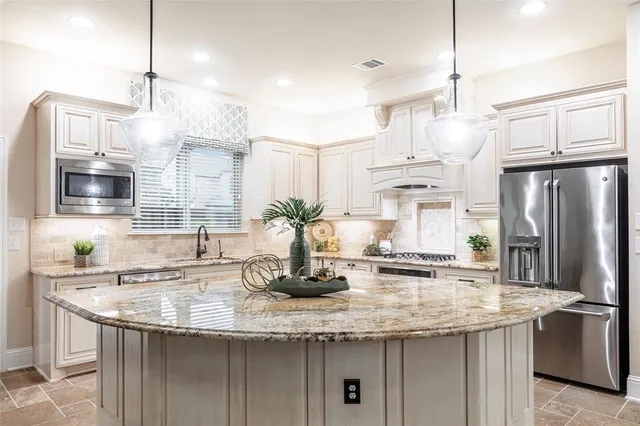 a kitchen with stainless steel appliances granite countertop a sink a refrigerator a stove and microwave