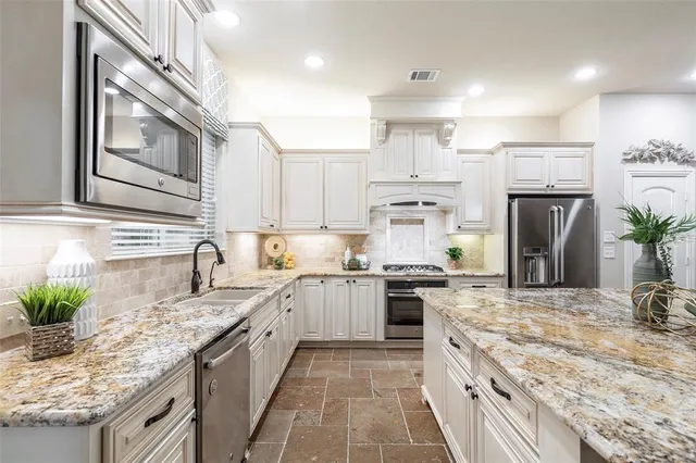 a large kitchen with granite countertop a sink a counter top space stainless steel appliances and cabinets