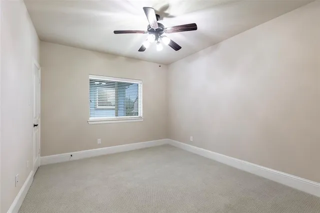 an empty room with windows and chandelier fan