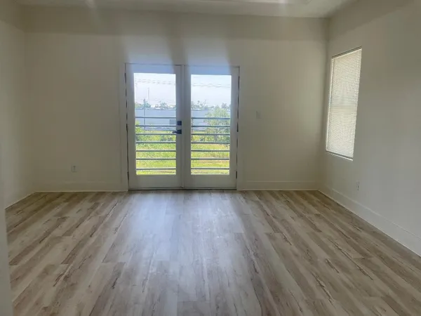 an empty room with wooden floor and windows