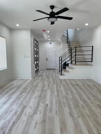 an empty room with wooden floor ceiling fan and windows