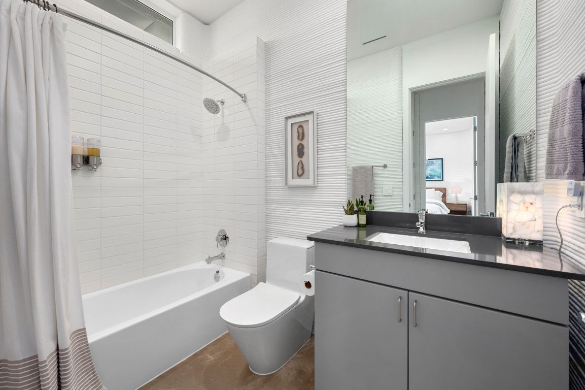 221 Lone Ranger Trail Georgetown, TX 78628 - Photo 22 of 35 a bathroom with a granite countertop sink a toilet a mirror a bathtub and shower