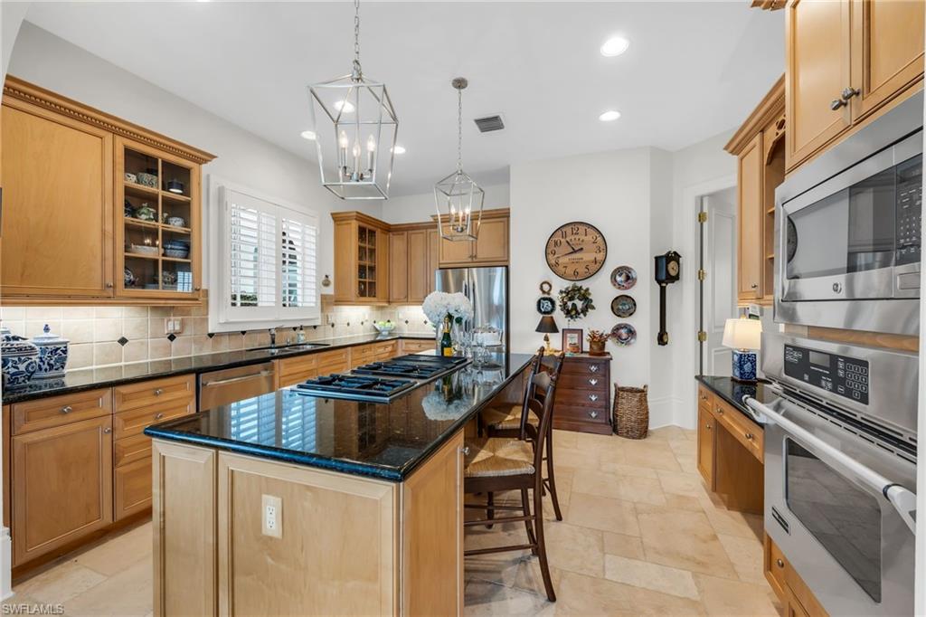 2629 Sorrel Way Naples, FL 34105 - Photo 24 of 43 a kitchen with stainless steel appliances granite countertop a stove top oven a sink a dining table and chairs