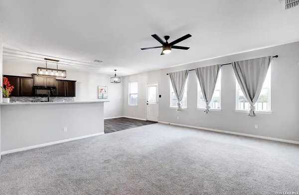 a view of an empty room with a window and a kitchen