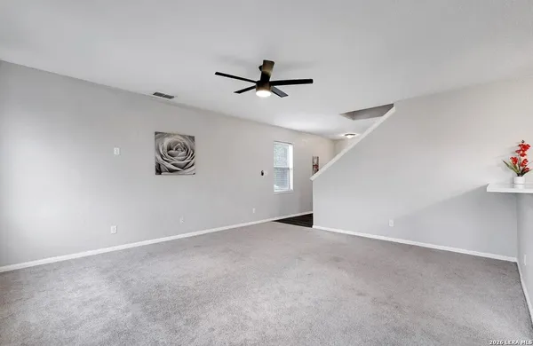 an empty room with windows and fan