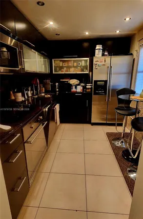 a kitchen with stainless steel appliances granite countertop a refrigerator and chairs