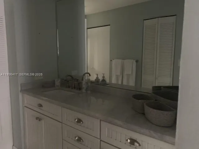 a bathroom with a granite countertop sink and white cabinets