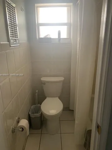 a white toilet sitting in a bathroom next to a window