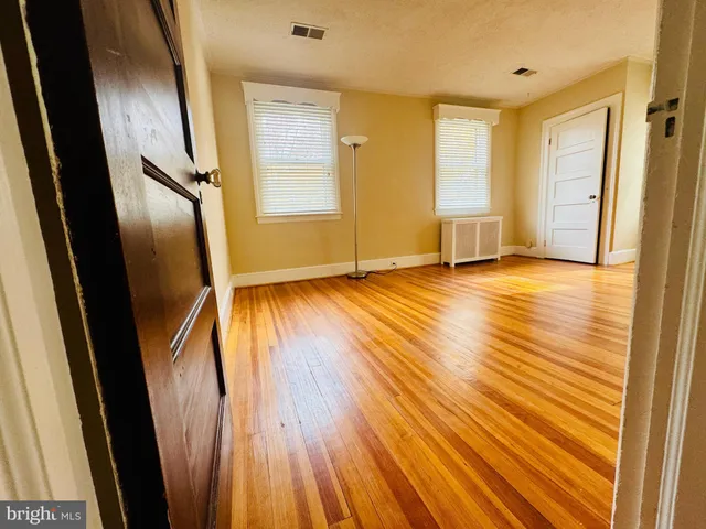 a view of an empty room with window and wooden floor