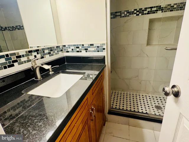 a bathroom with a granite countertop sink a mirror and shower