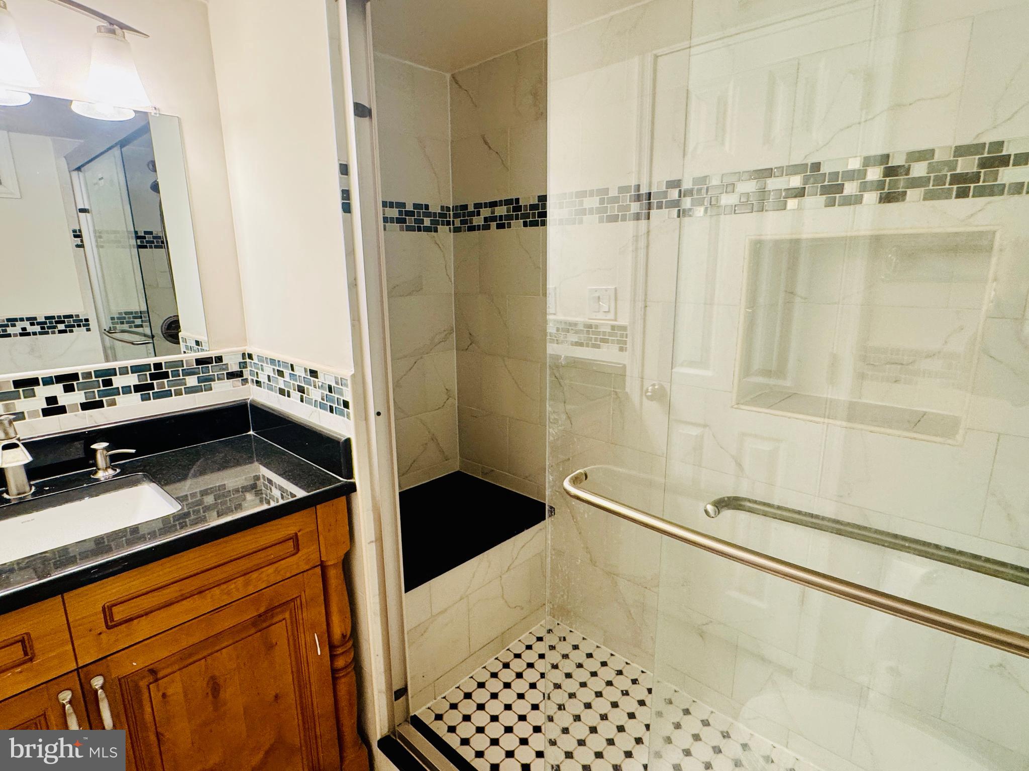 3902 Hadley Square West Baltimore, MD 21218 - Photo 32 of 38 a bathroom with a granite countertop sink a mirror and shower