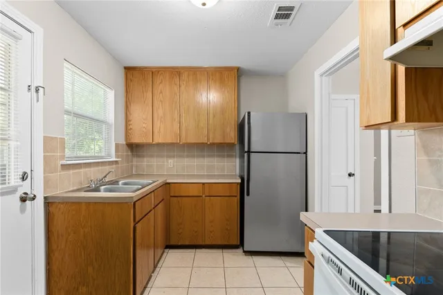 a kitchen with a sink refrigerator and cabinets