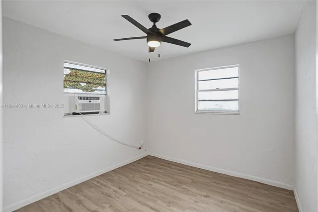 an empty room with wooden floor and ceiling fan