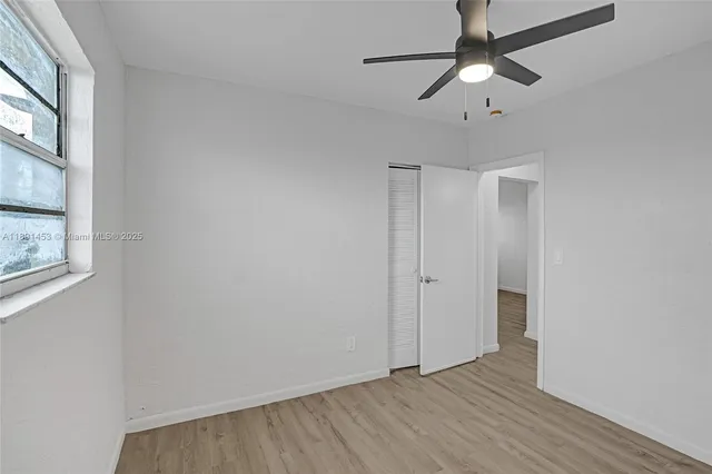 an empty room with wooden floor fan and windows