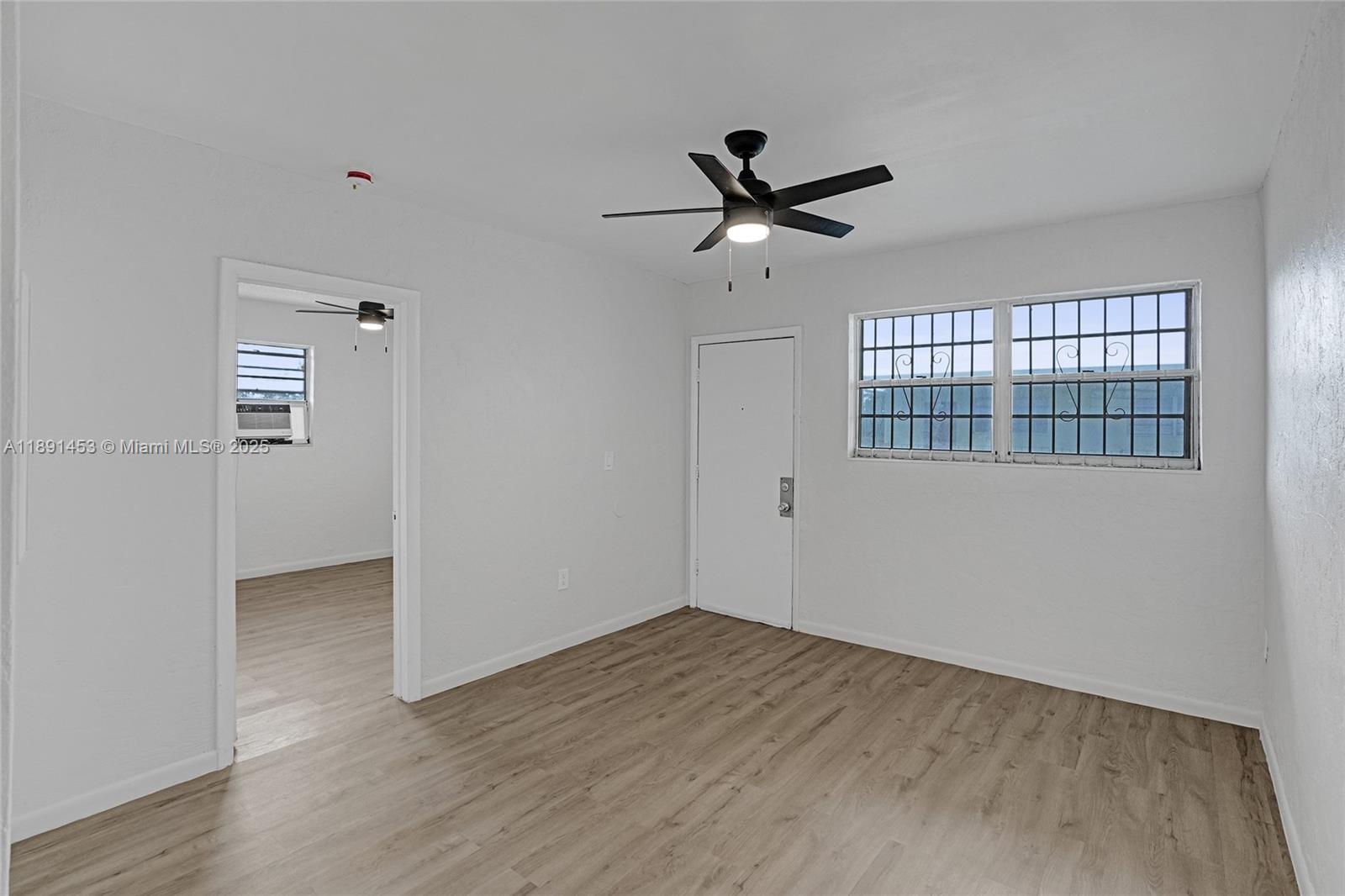 14100 Northwest 24th Court, Unit 303 Opa-Locka, FL 33054 - Photo 3 of 21 a view of empty room with wooden floor and fan