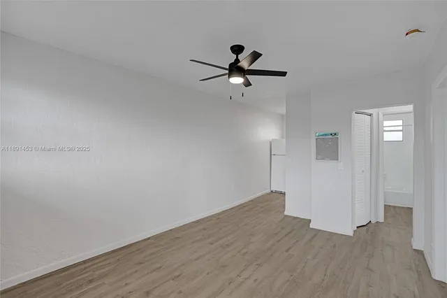 a view of empty room with wooden floor and ceiling fan