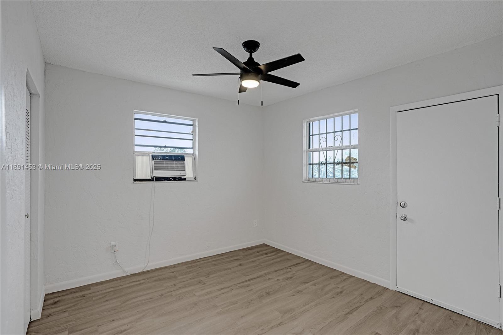 14100 Northwest 24th Court, Unit 303 Opa-Locka, FL 33054 - Photo 6 of 21 a view of empty room with wooden floor and fan