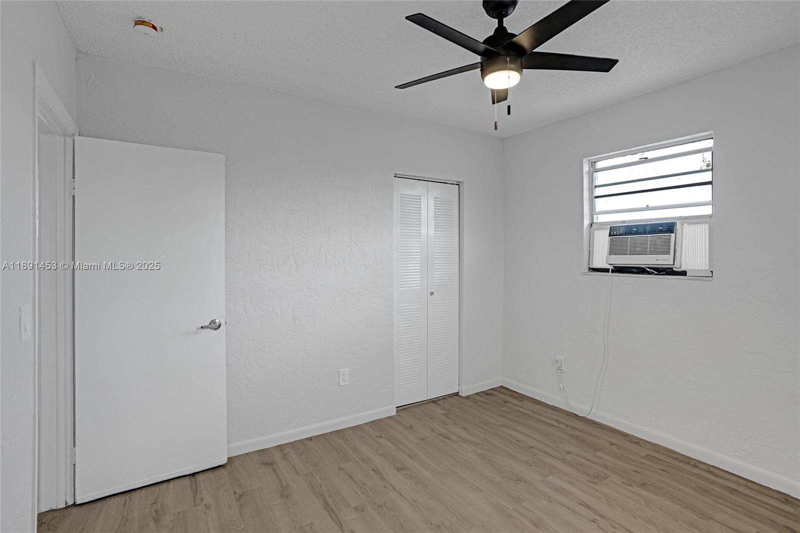 14100 Northwest 24th Court, Unit 303 Opa-Locka, FL 33054 - Photo 7 of 21 a view of empty room with wooden floor and fan