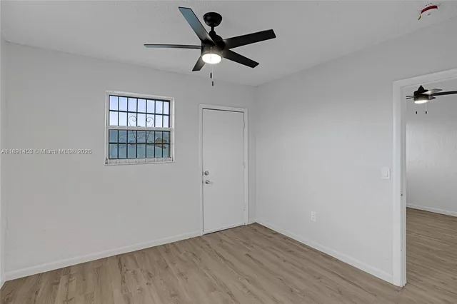 an empty room with wooden floor fan and windows